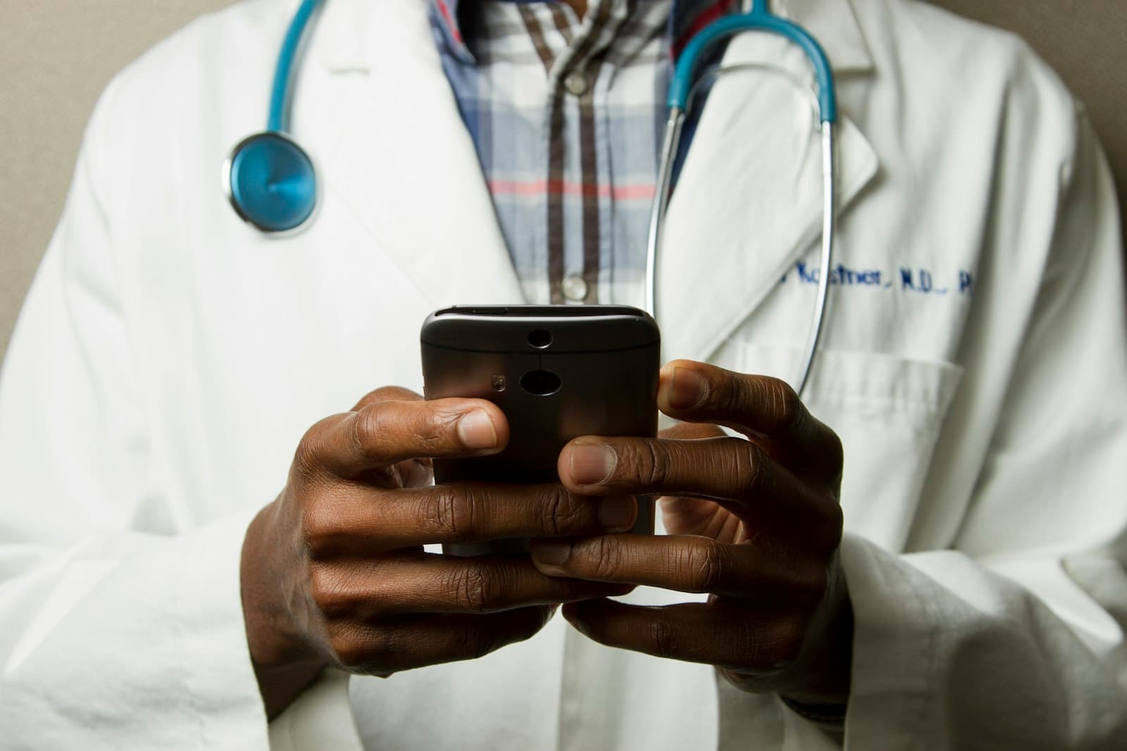 A doctor in a white coat replying to messages on a phone